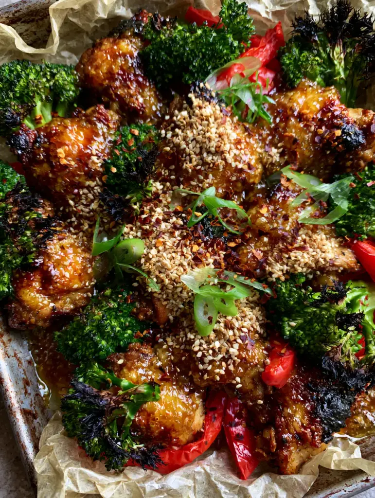 Quick Recipes: The Ultimate Honey Garlic Sheet Pan Chicken with Blistered Skin 2 Macro view of seared chicken thighs with a bubbling amber glaze and sesame seeds. (Quick Recipes)