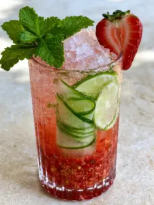 Close up of strawberry cucumber limeade showing the thick layer of muddled strawberry pulp and sparkling water bubbles.