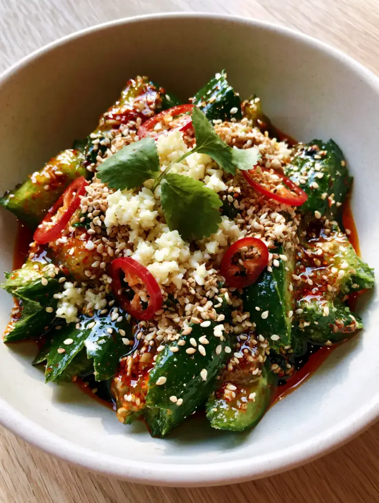 Cucumber Salad Recipes: The Viral Asian Smashed Side Dish You Need 1 Side view of an Asian cucumber salad in a white bowl on a light wooden surface. (cucumber salad recipes)