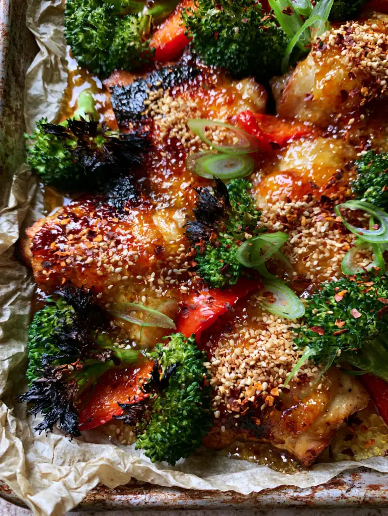 Quick Recipes: The Ultimate Honey Garlic Sheet Pan Chicken with Blistered Skin 1 Rustic metal sheet pan with charred broccoli florets and honey garlic chicken pieces.