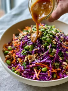 A smartphone photo showing the hyper-realistic textures of shredded red cabbage and julienned carrots in an Asian Crunch Salad.