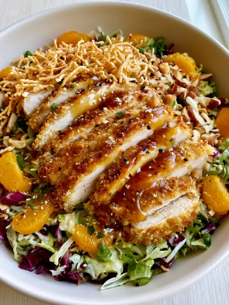 Oriental Chicken Salad with Crispy Panko Chicken and Ginger Dressing 2 Close up of crispy golden-brown panko-breaded chicken strips topped with sesame seeds and green scallions on an Oriental Chicken Salad.