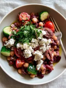 Overhead view of a vegetarian bean salad showing glossy chickpeas and red kidney beans with fresh herbs. (vegetarian bean salad)