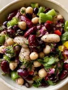Close-up macro shot of a five bean salad featuring bright green beans and red bell pepper jewels. (five bean salad)