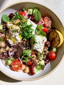 Detailed view of za'atar bean salad showing glistening olive oil dressing, dark green spice flecks, and fresh mint leaves.