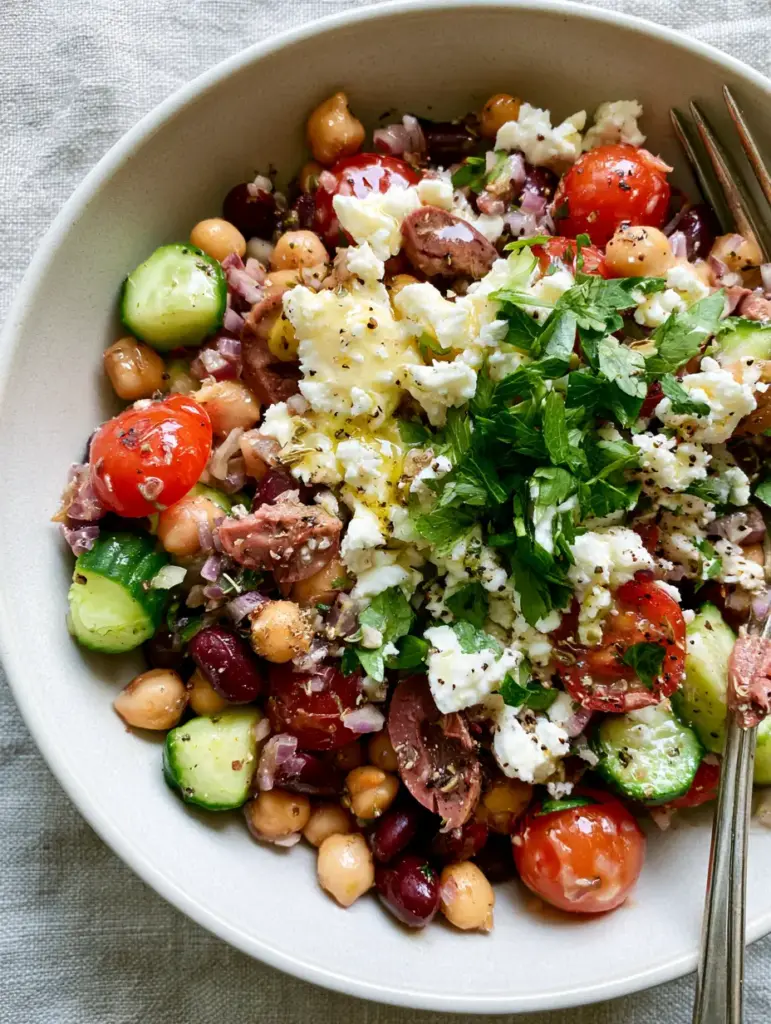 Close up of halved cherry tomatoes and crumbled feta in a vegetarian bean salad.