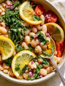 Extreme top-down close-up of Lemon Basil Bean Salad in a matte white bowl with translucent olive oil glaze.