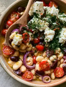 Vibrant Mediterranean Butter Bean Salad in a shallow rustic ceramic bowl with a wooden spoon. (butter bean salad)