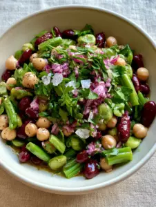 Top-down handheld photo of a three-bean salad showing the glossy texture of kidney beans and fresh parsley garnish. (three-bean salad)