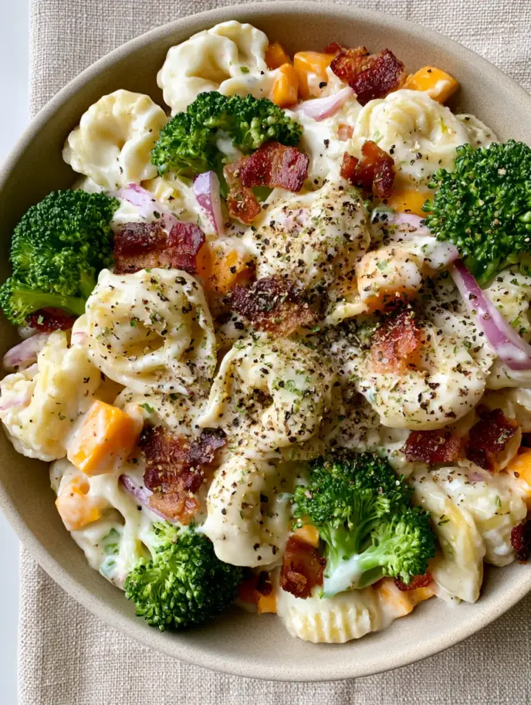 Tortellini Broccoli Salad with Crispy Bacon and Sharp Cheddar 1 Close up of Tortellini Broccoli Salad highlighting the sharp orange cheddar cubes and bright green raw broccoli florets.