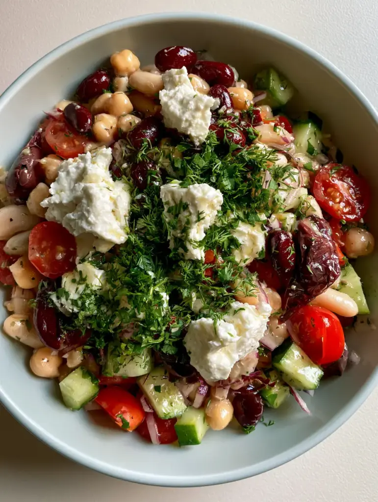 Close up of chunky feta and wrinkled kalamata olives in a Mediterranean three-bean salad.