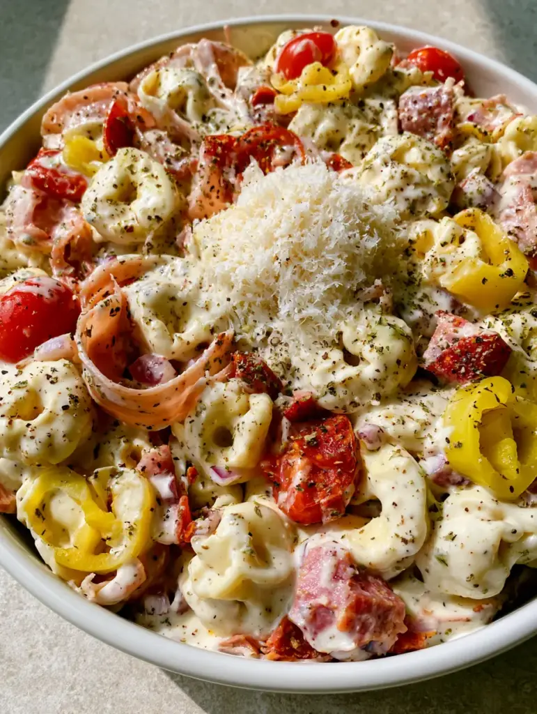 Italian Grinder Tortellini Salad with Creamy Herb Dressing 1 Italian Grinder Tortellini Salad in a white ceramic bowl on a grey stone countertop in natural light.
