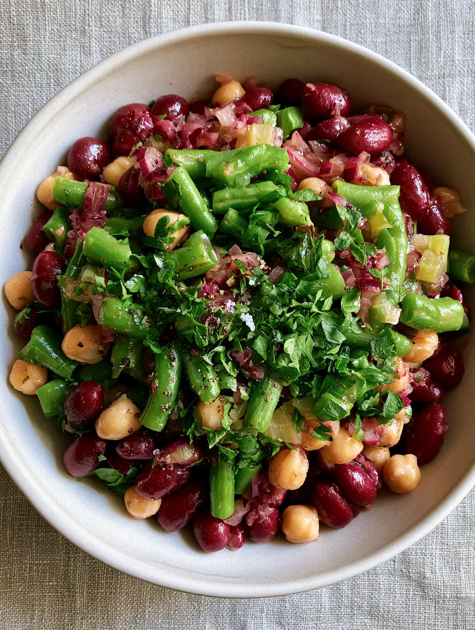 3 Bean Salad with Glossy Cider Vinaigrette and Fresh Herbs 4 Smartphone photo of 3 bean salad in a matte white bowl, showing glossy mahogany beans and emerald green beans.