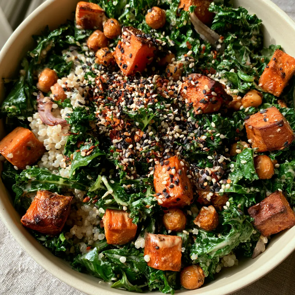Quinoa Kale Salad with Roasted Sweet Potatoes and Lemon Tahini 1 Close-up of roasted sweet potatoes with charred edges mixed into a quinoa kale salad with white and black sesame seeds.