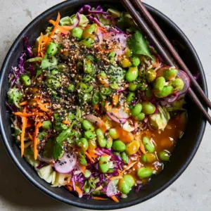 Close up of Japanese Edamame Salad showing the glossy sesame ginger dressing and toasted black and white sesame seeds.