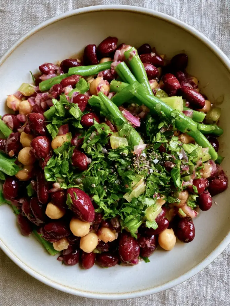 3 Bean Salad with Glossy Cider Vinaigrette and Fresh Herbs 1 Close-up of vibrant green beans and kidney beans in a shimmering vinegar dressing with cracked black pepper.