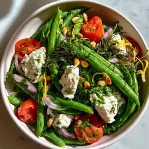 Overhead view of a glossy green bean salad with lemon zest and fresh dill garnishes. (green bean salad)