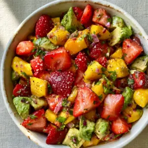 Close-up of Avocado Strawberry Mango Salsa with glistening lime juice and coarse sea salt crystals.